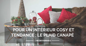 un plaid posé sur un canapé avec des coussins et une table avec des décorations de noël