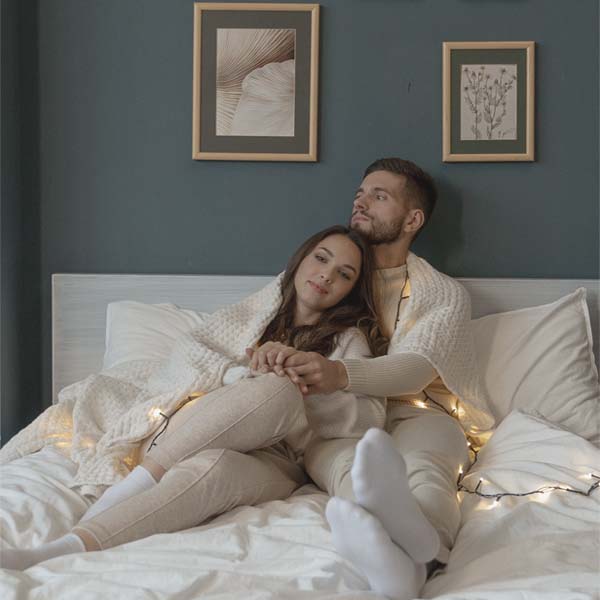 A smiling couple wrapped in an off-white throw
